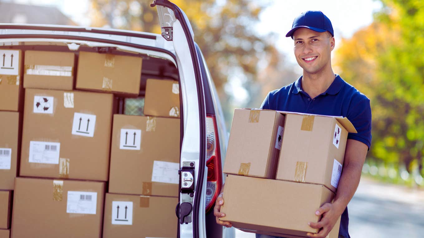 Amazon delivery driver holding boxes in front of truck