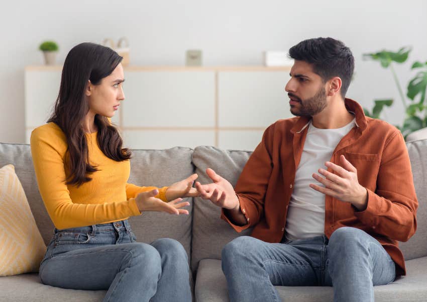 man and woman in relationship arguing on couch in living room