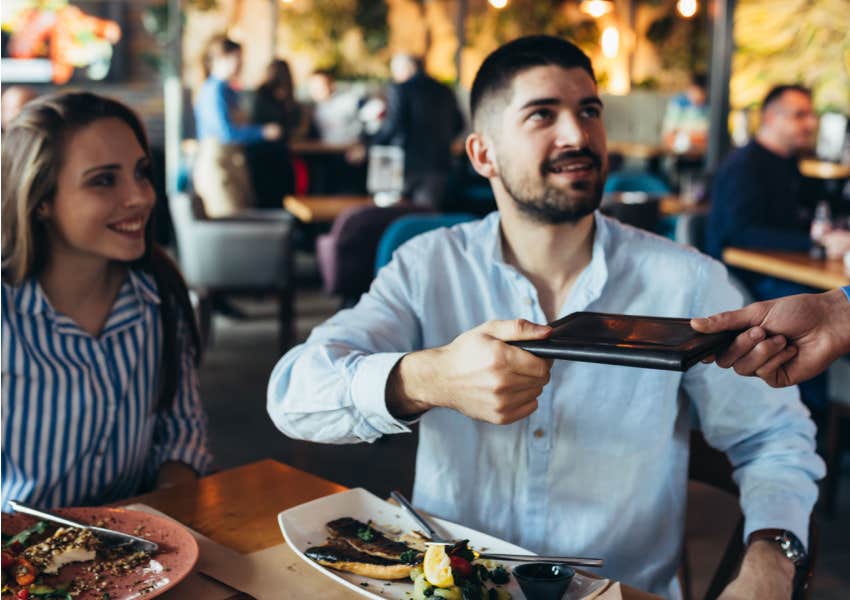 man paying for the bill for lunch at restaurant with female friend