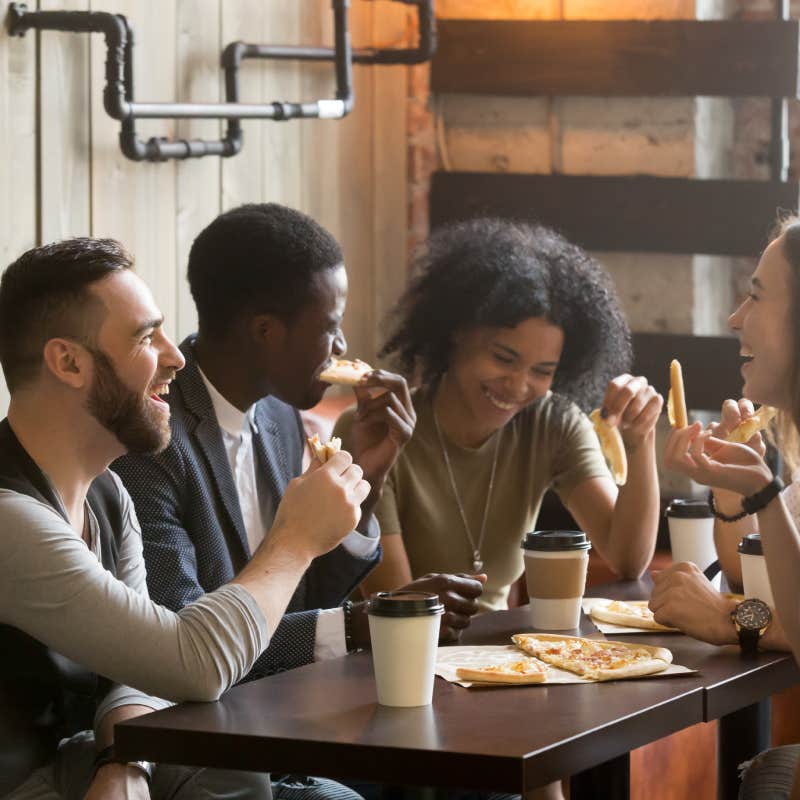 happy young people eating pizza in pizzeria expecting man to pay