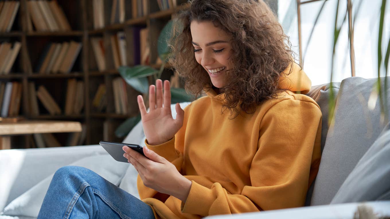 young woman sitting on the couch using her phone