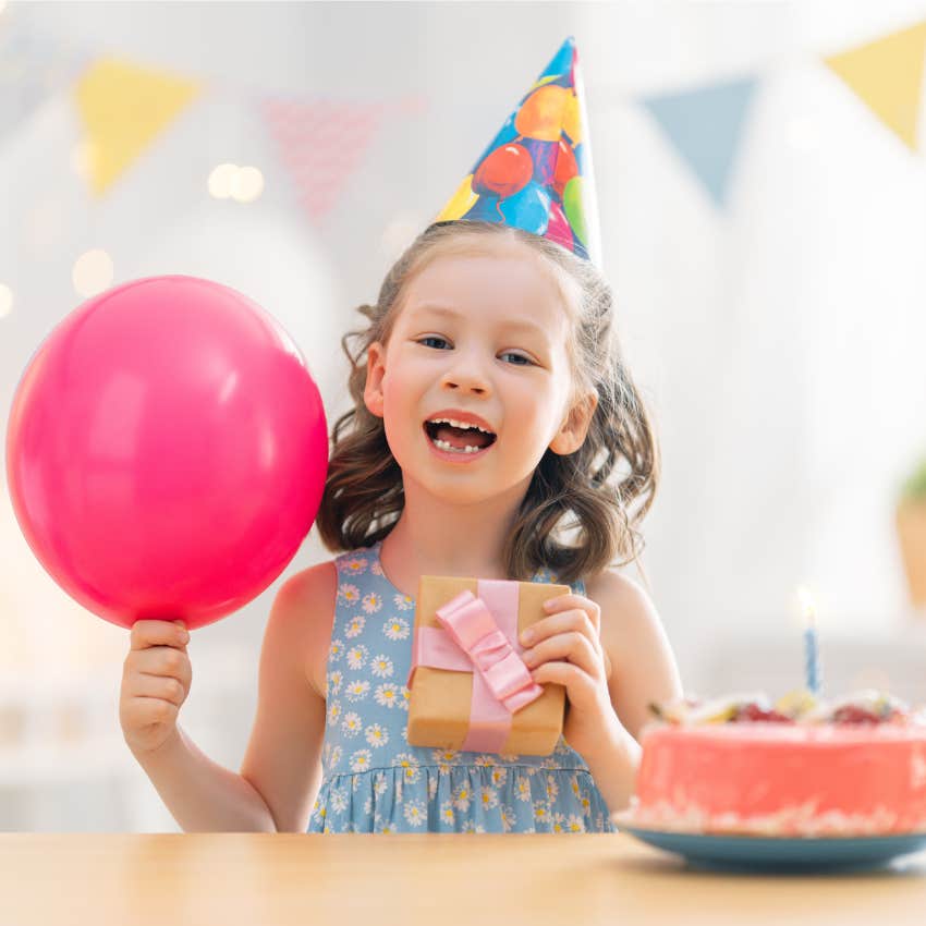 little girl holding balloon with cake