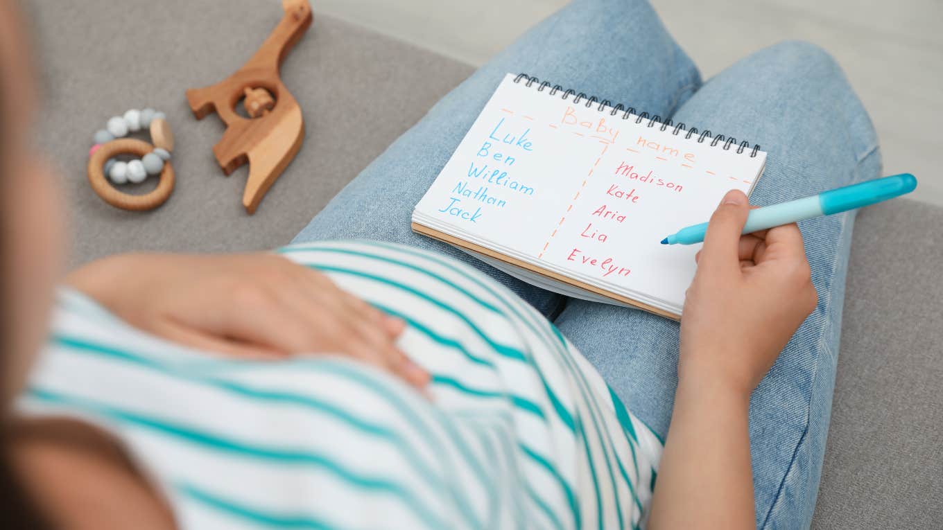 pregnant woman sitting on couch making list of baby names