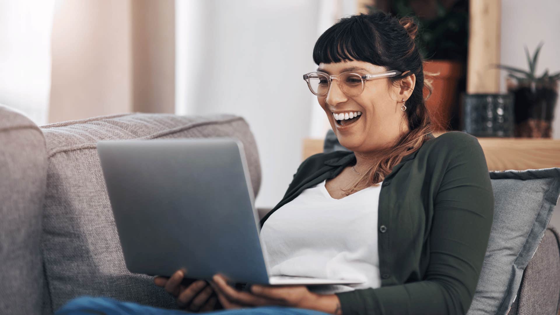 woman laughing at funny movie on laptop