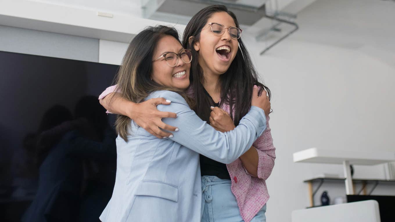 two female employees laughing and hugging