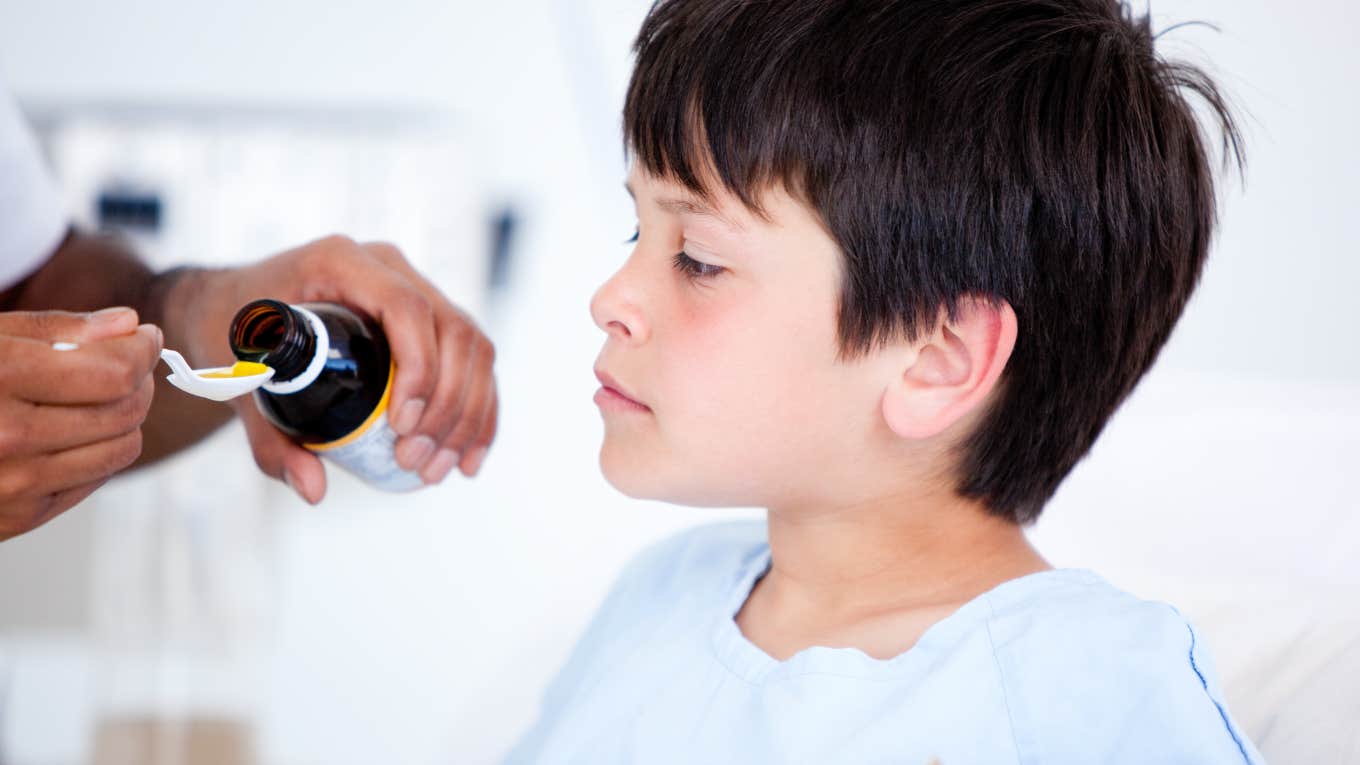 little boy being given liquid medicine from a spoon