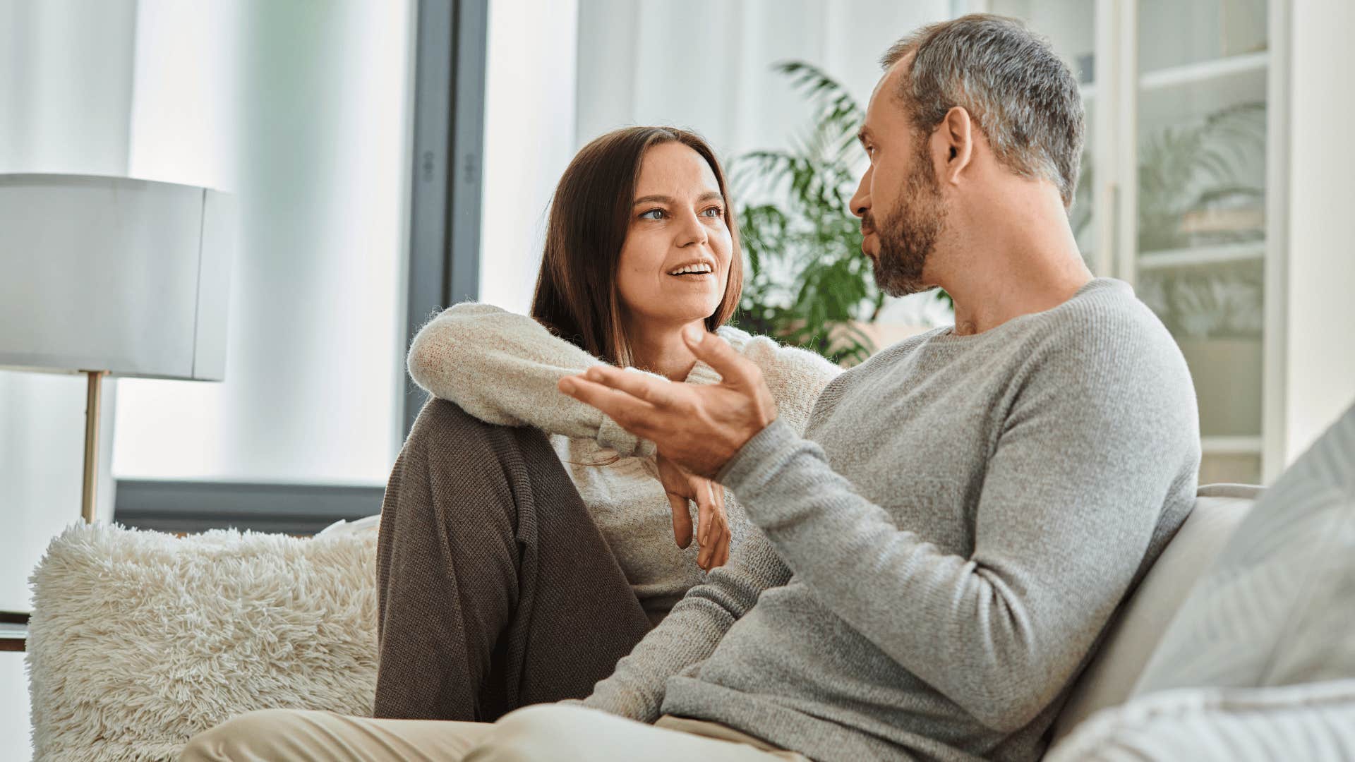 man and woman talking on couch