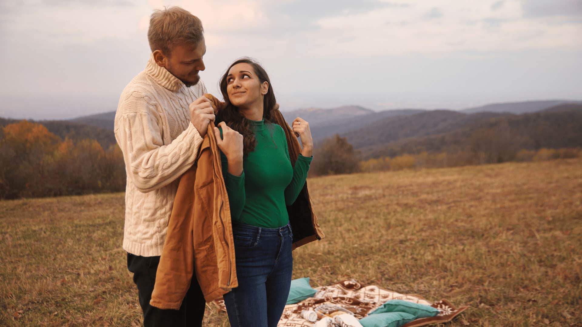 man being old-fashioned and offering his jacket to woman