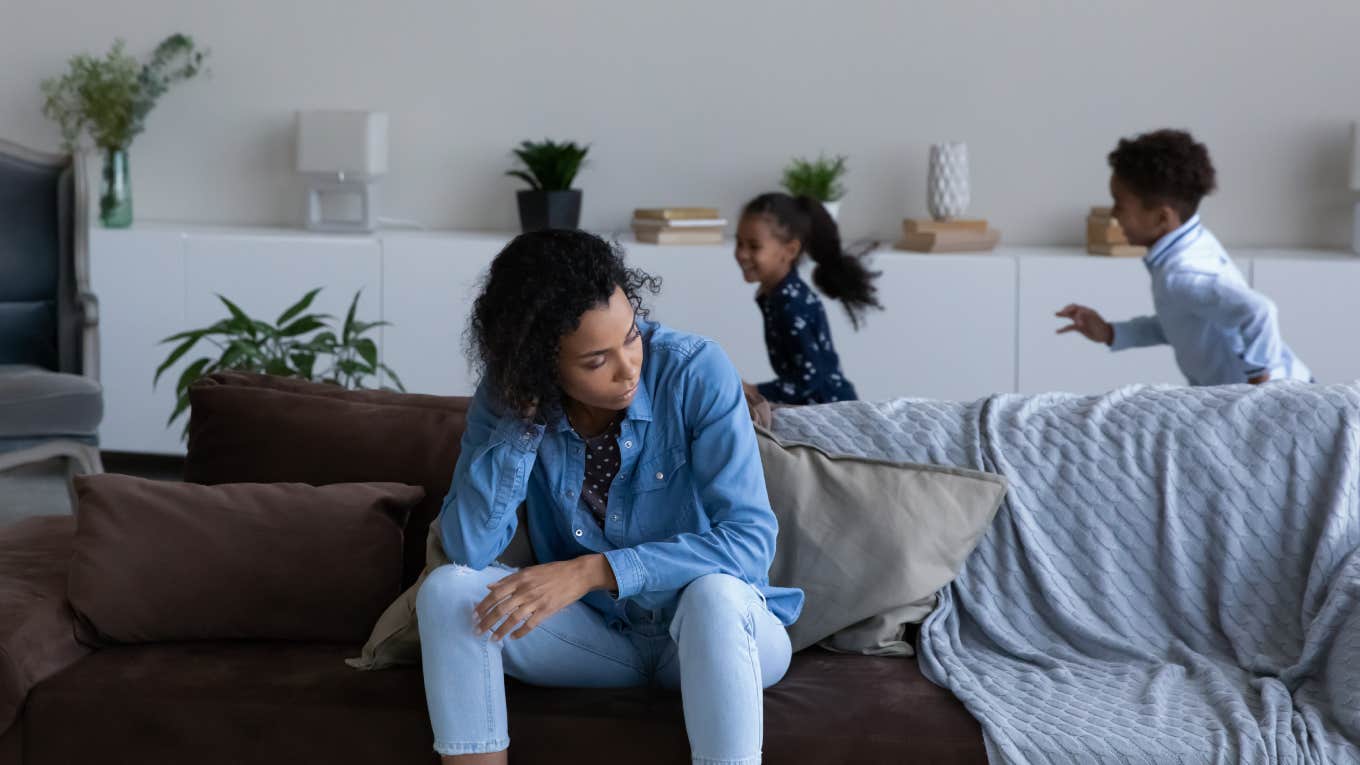 mother feeling tired of noisy little children playing around her