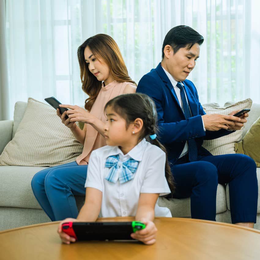 parents and child all on separate tech devices in the same room