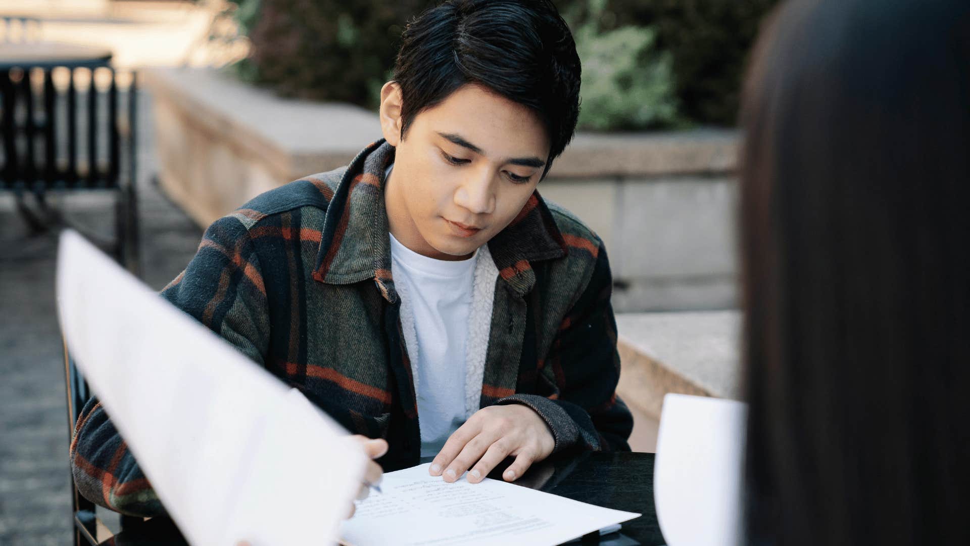 young man reading and studying outside with woman