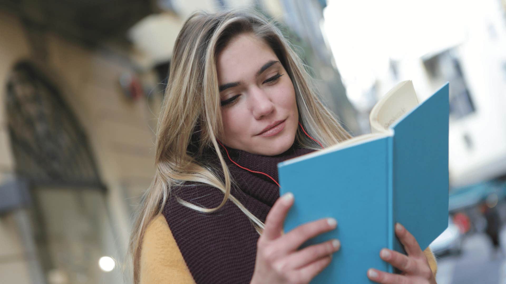 woman reading book with headphones in