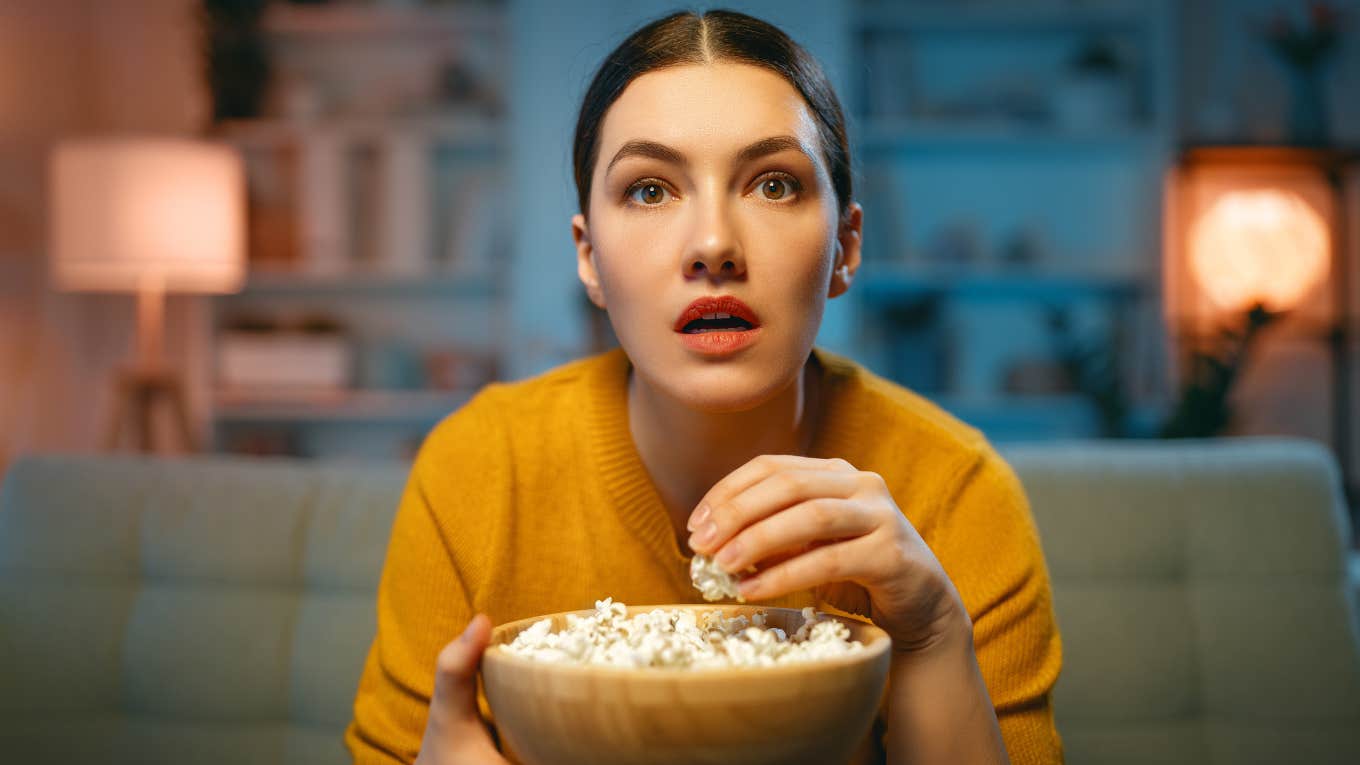 woman with popcorn watching engaging movie