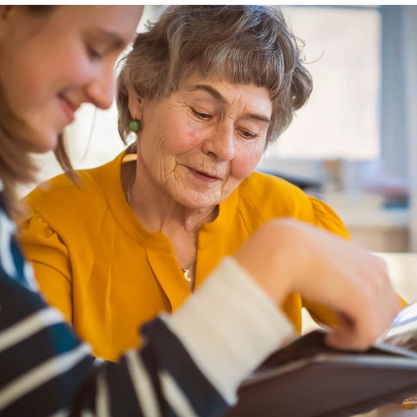 Woman looking at a photo album with her mom. 