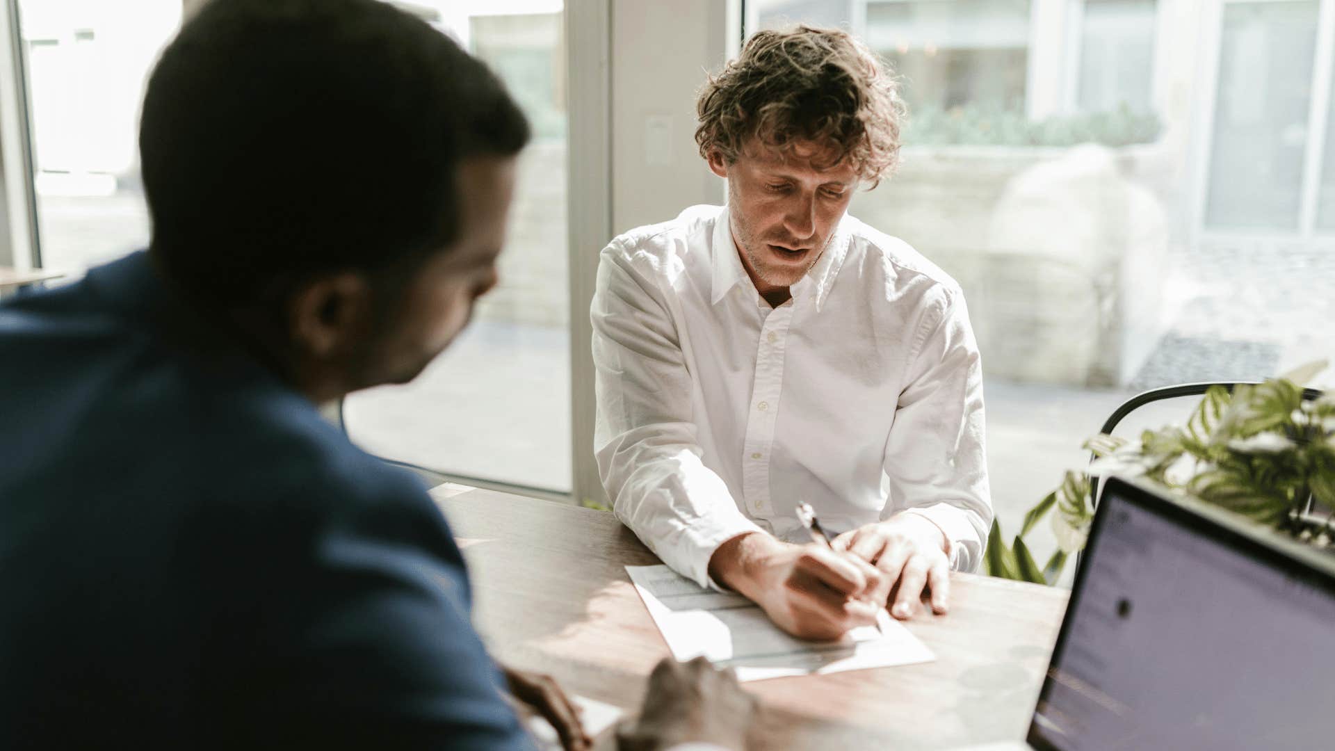 intelligent man filling out paper work while other man watches