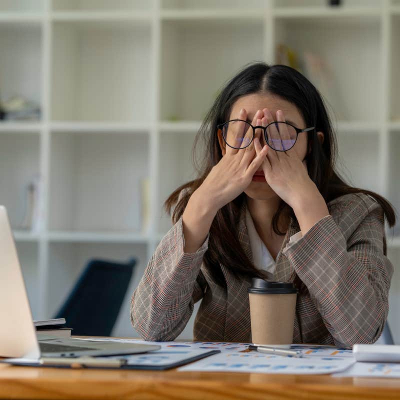 exhausted businesswoman sitting at desk with laptop