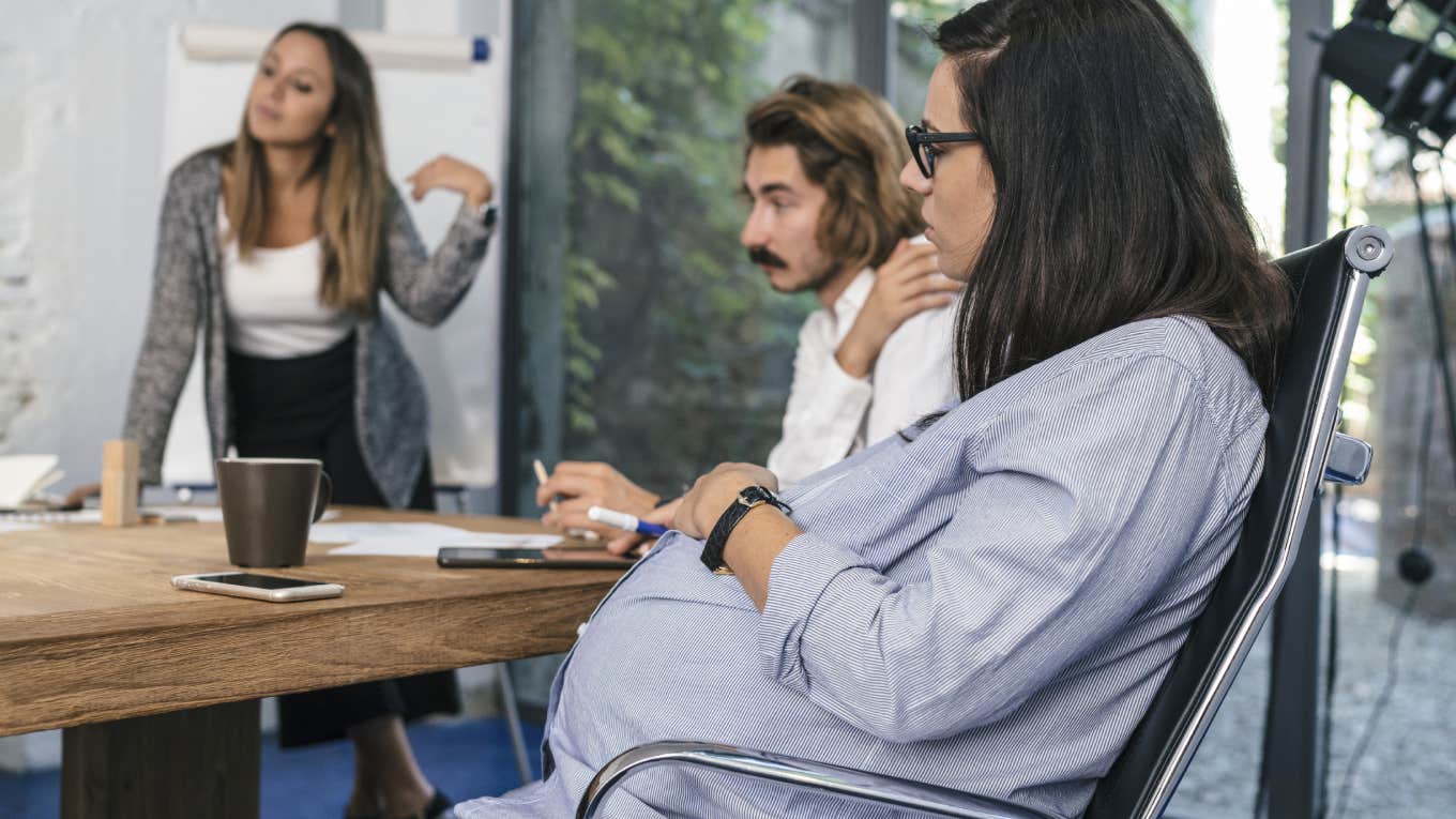 pregnant woman sitting in meeting at work with coworkers