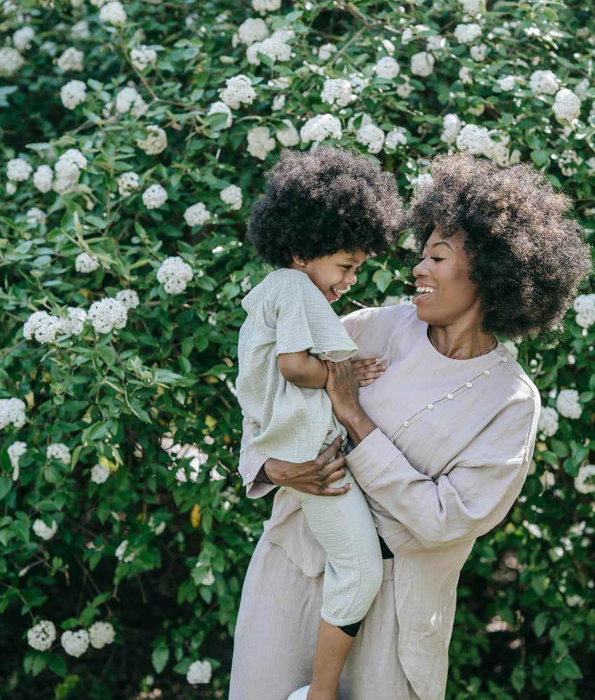 mom holding child in front of flowers