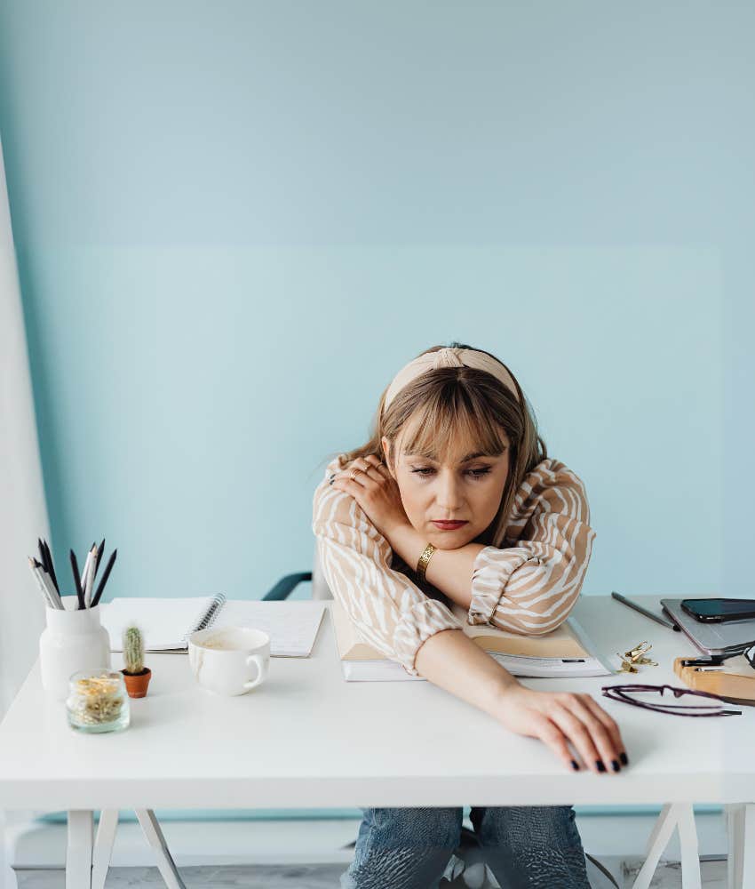 sad worker sitting at a desk with her head on her arms