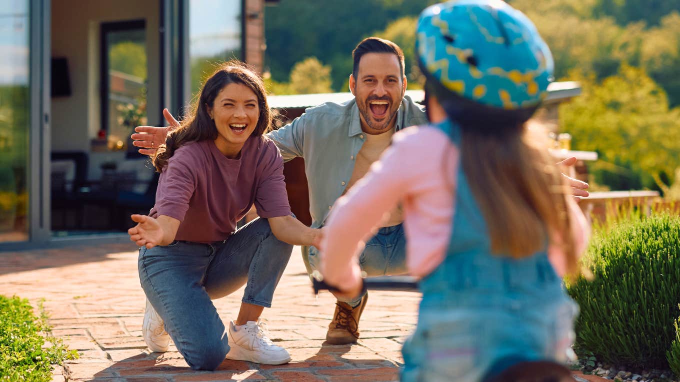 happy parents watching daughter ride a bike