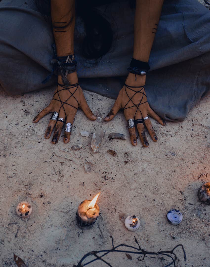 She places hands on earth in a ritual circle of candles