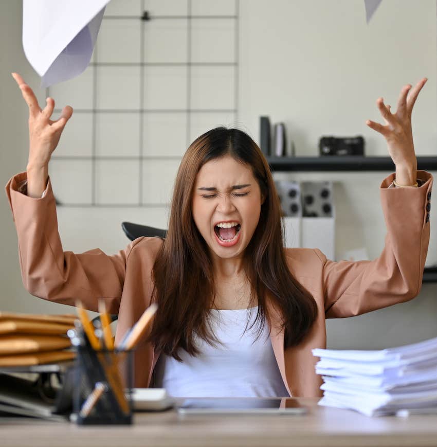 Frustrated worker throws papers in air, she is losing her edge