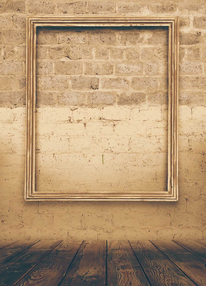 Empty artwork frame hangs on a brick wall