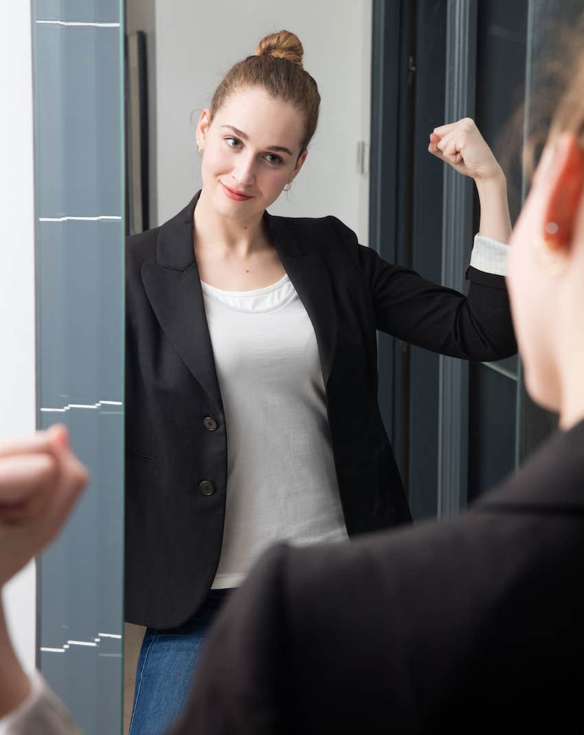 Confident woman looks in mirror, flexes, she is building and bigger, better life