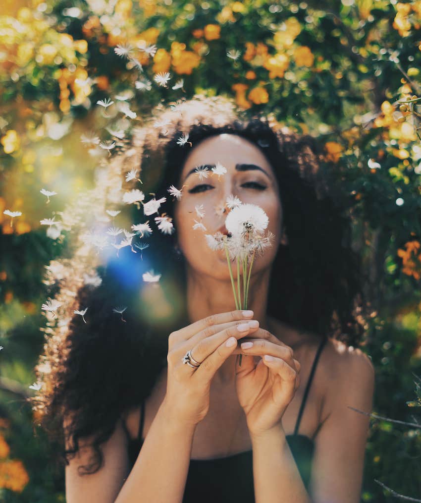 Woman blows on dandelion for good luck