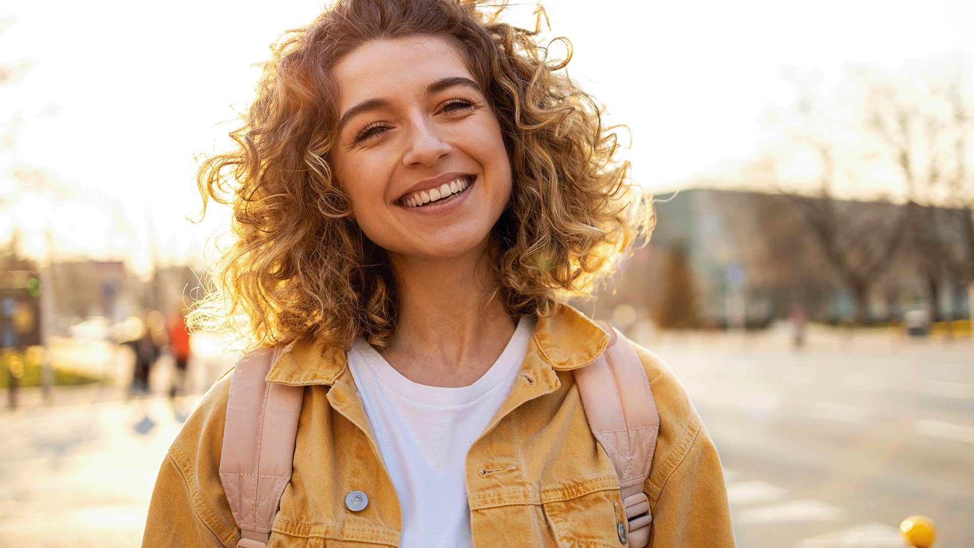 smiling woman with curly hair and yellow jacket