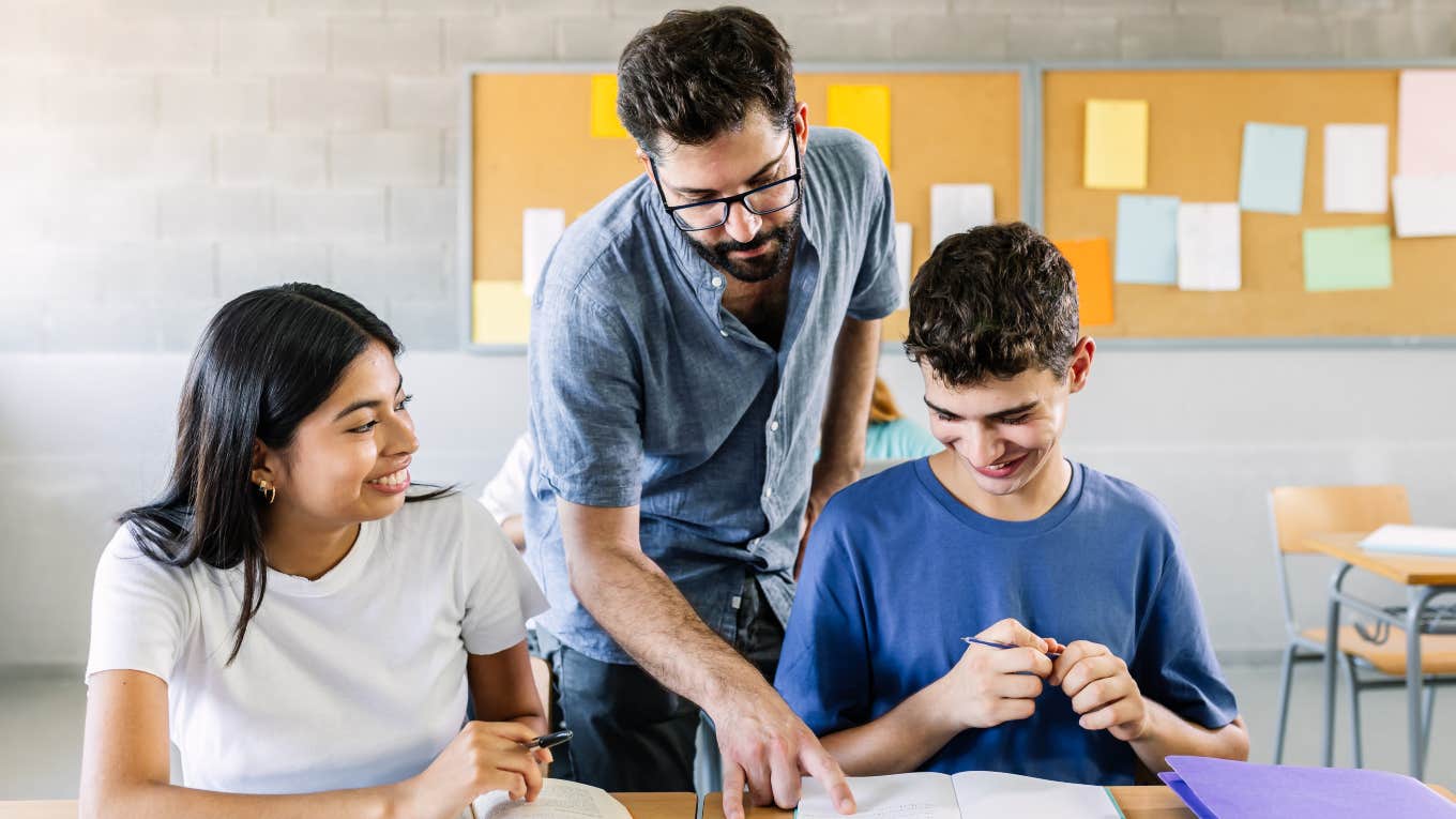 teacher helping high school students with their class work