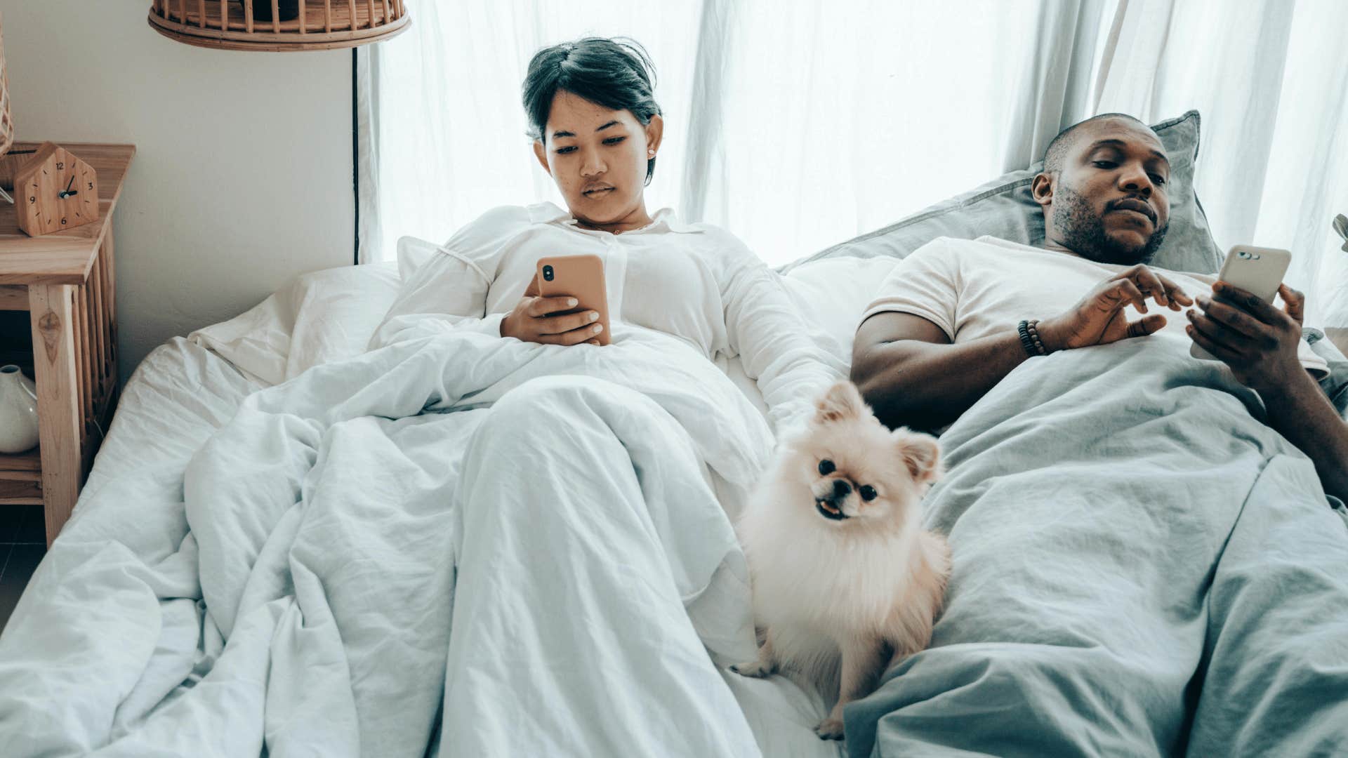 couple laying in bed on phones