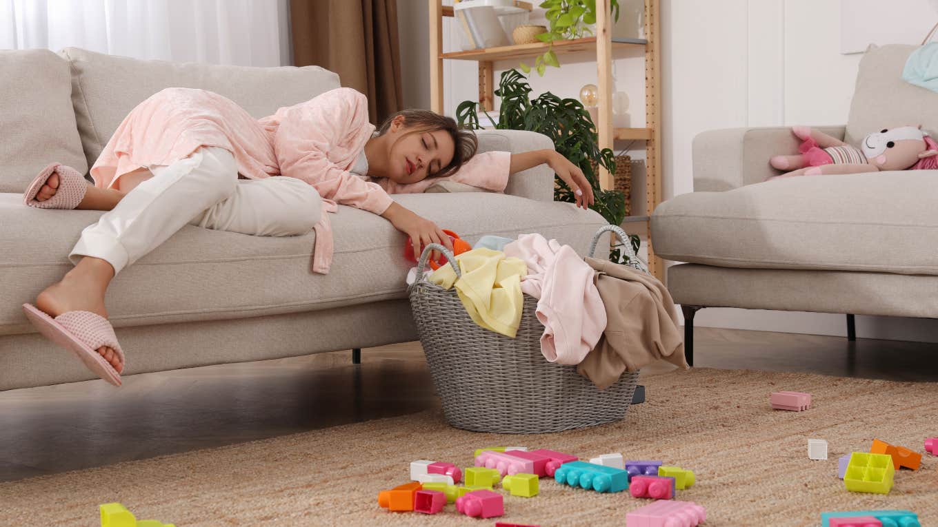 stressed woman laying on couch surrounded by toys and laundry