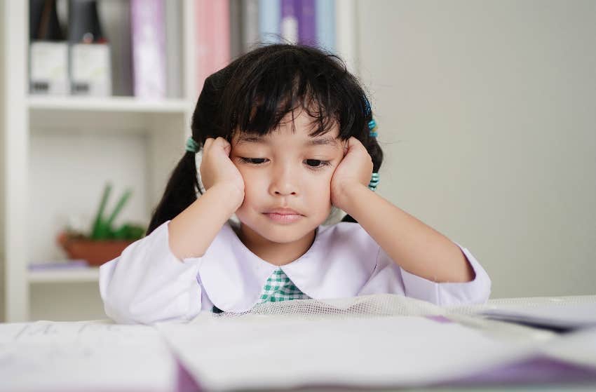 child propping up head while staring at an assignment