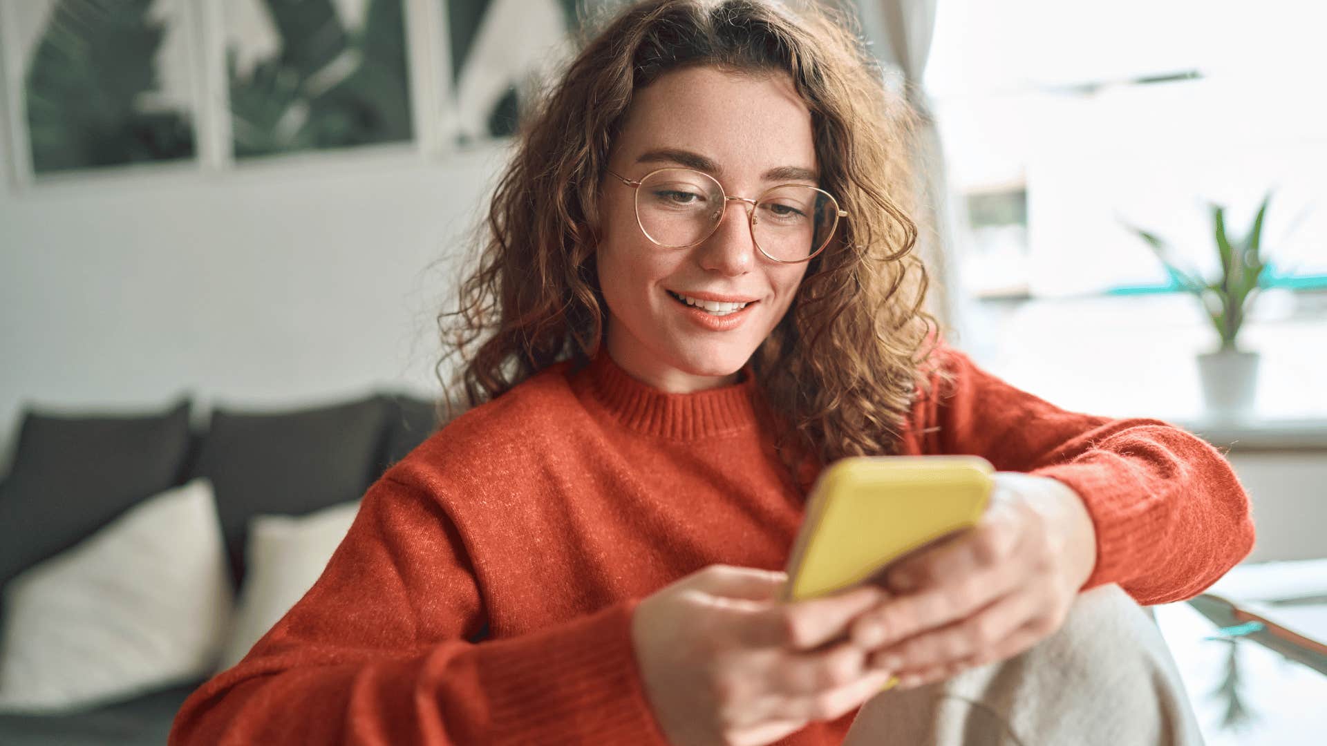 woman smiling while looking at phone