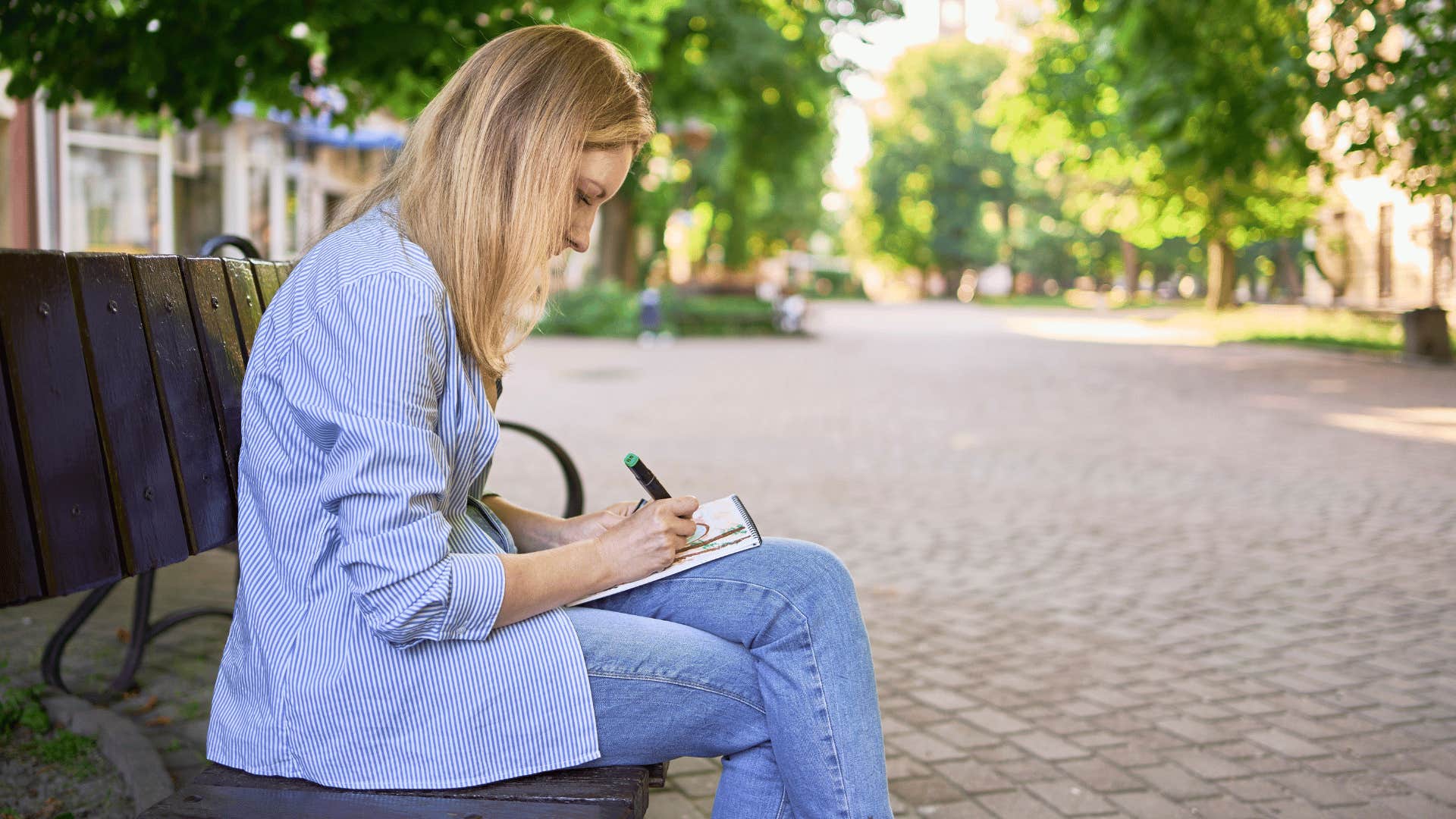 woman sitting on bench writing 