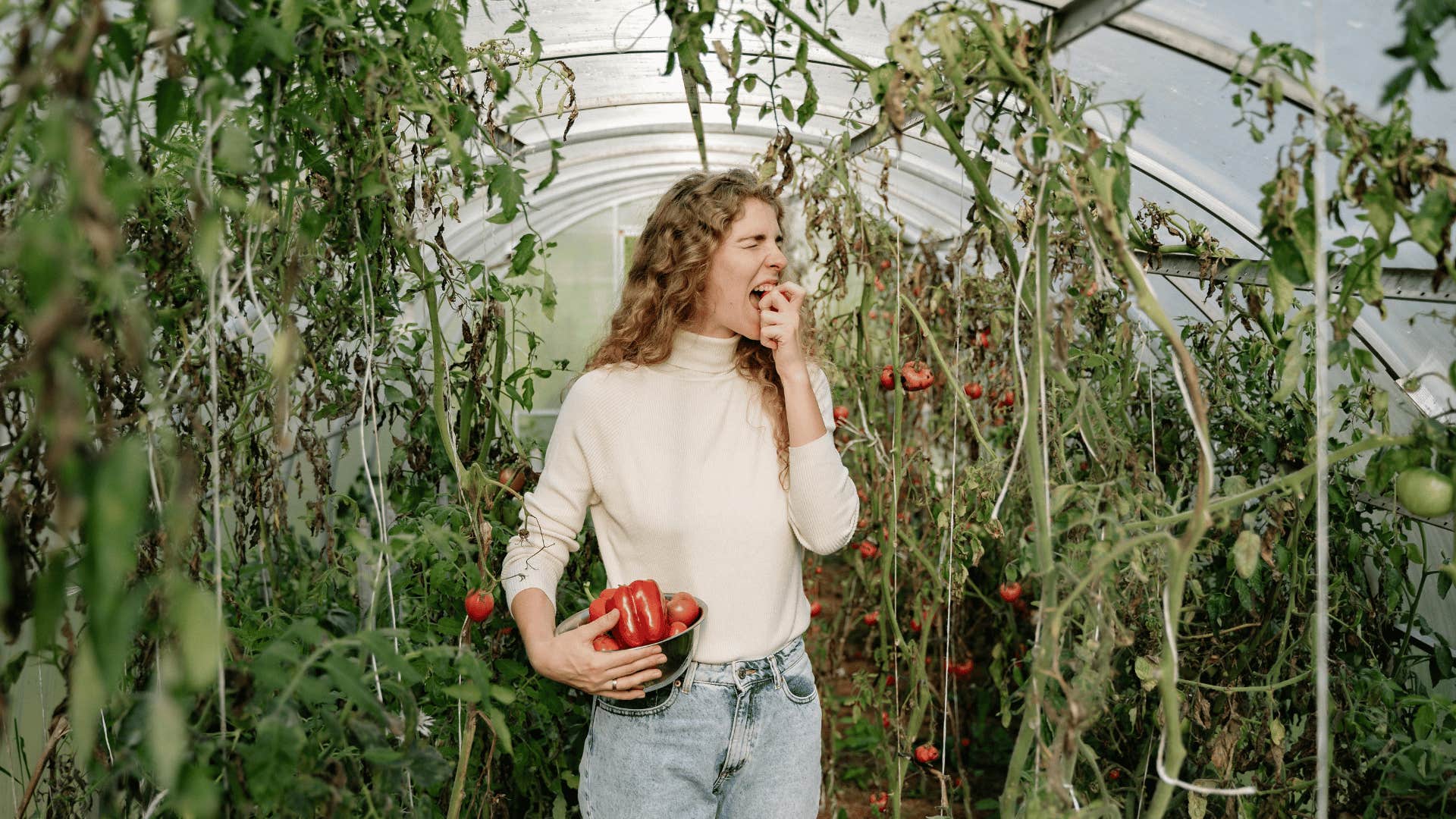 woman eating vegetables in greenhouse