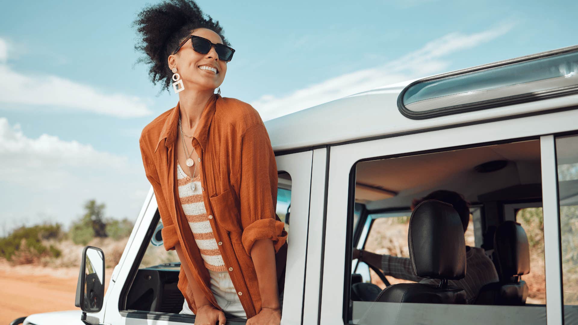 woman smiling at people while looking out of car