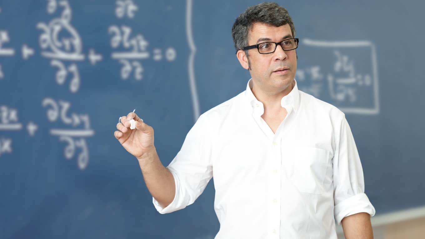 Physics professor teaching in front of chalkboard. 