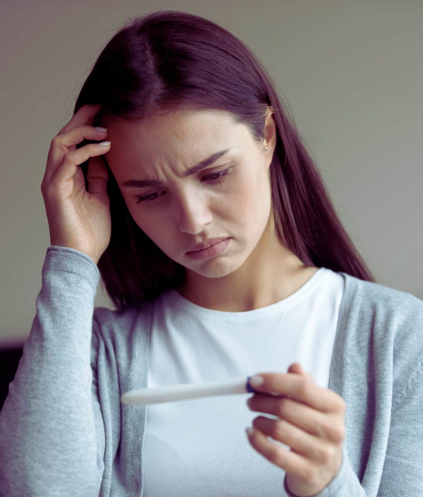 woman looking worried at pregnancy test results