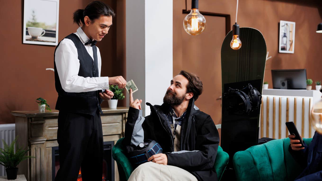 man handing waiter tip in hotel lobby