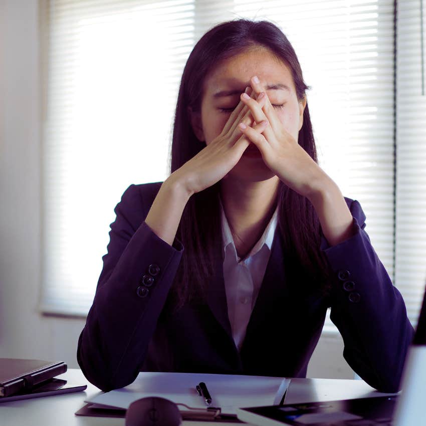 Woman with hands on her head feeling stressed at work