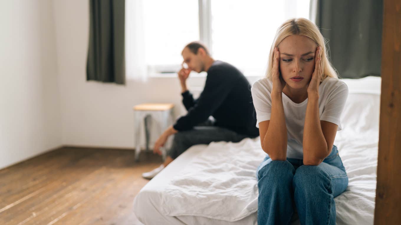 couple sitting separate on bed with backs turned ignoring each other after fight