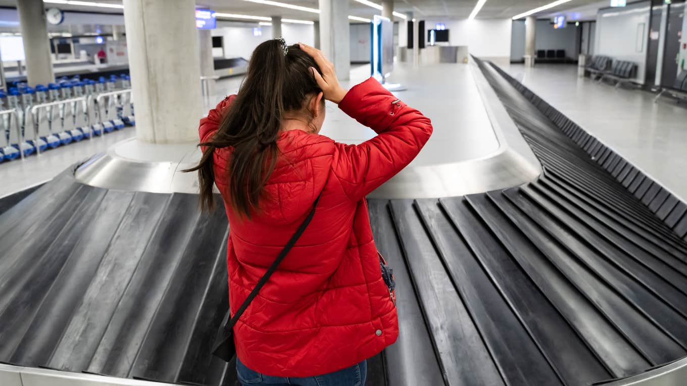 Woman realizing airline lost her luggage at baggage carousel