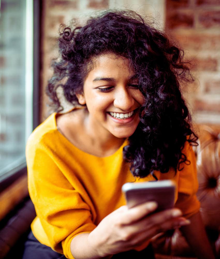 woman smiling while looking at phone