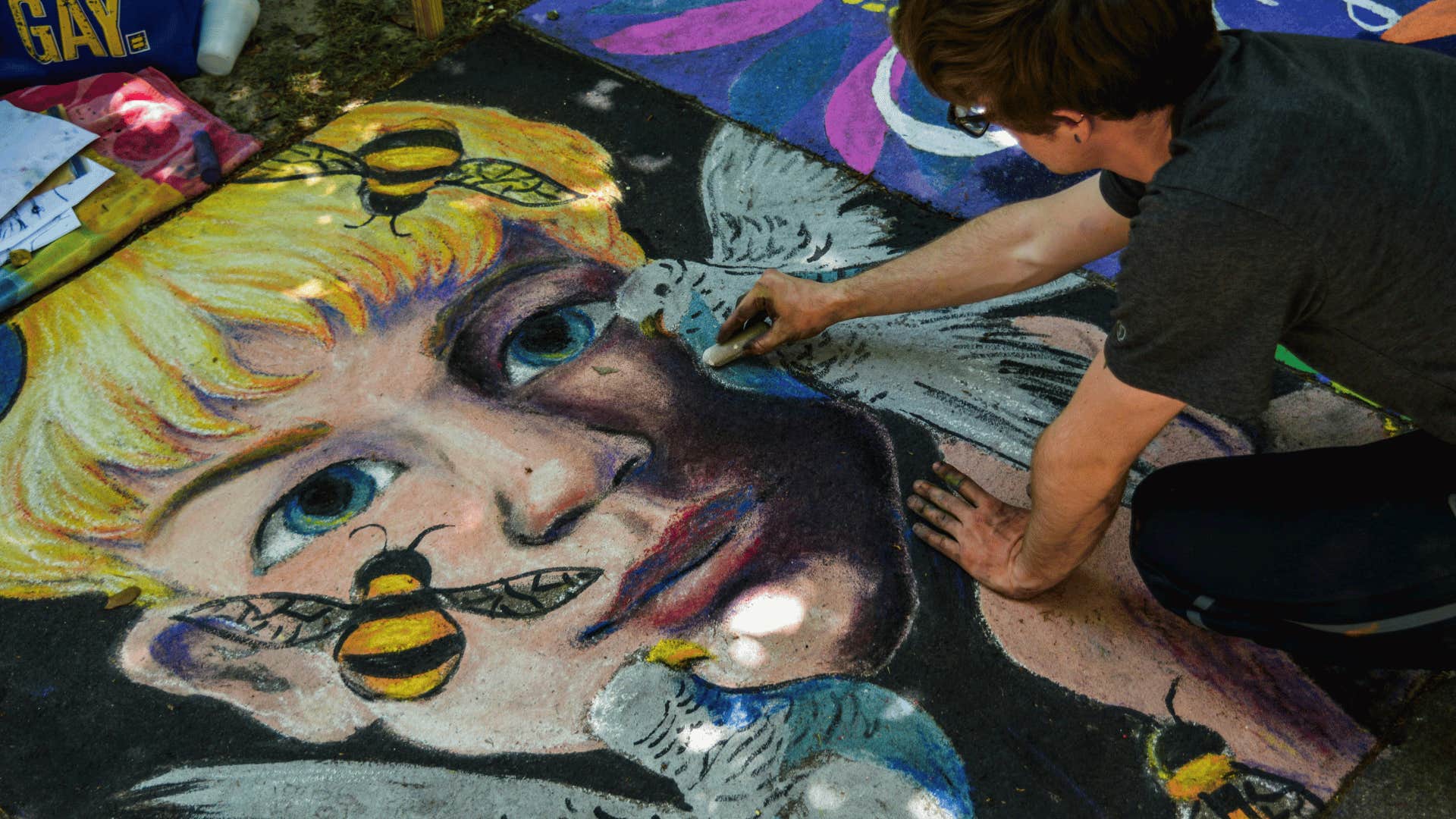 man working on chalk drawing on concrete floor