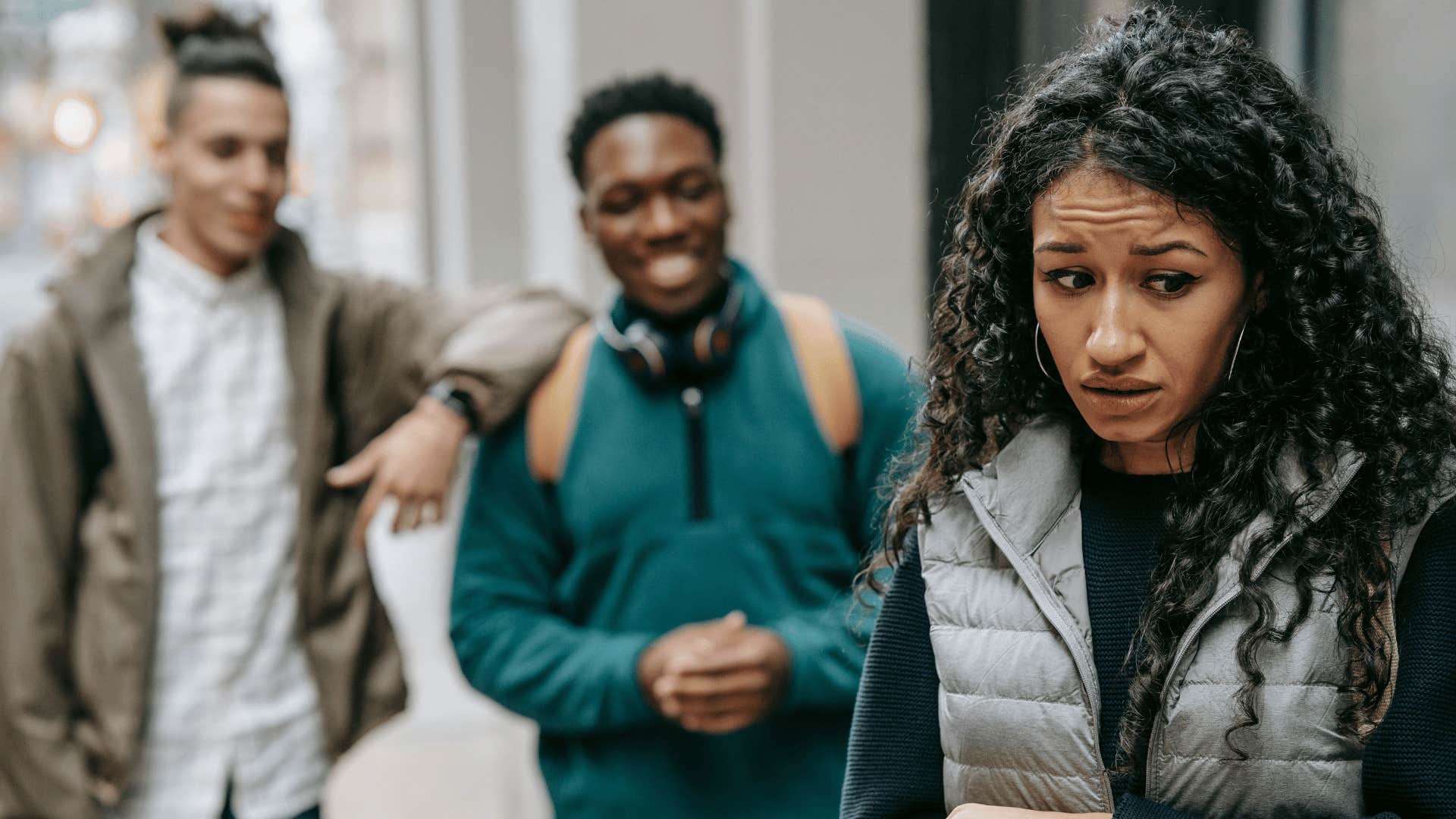 shy low self confident woman turned away from two men