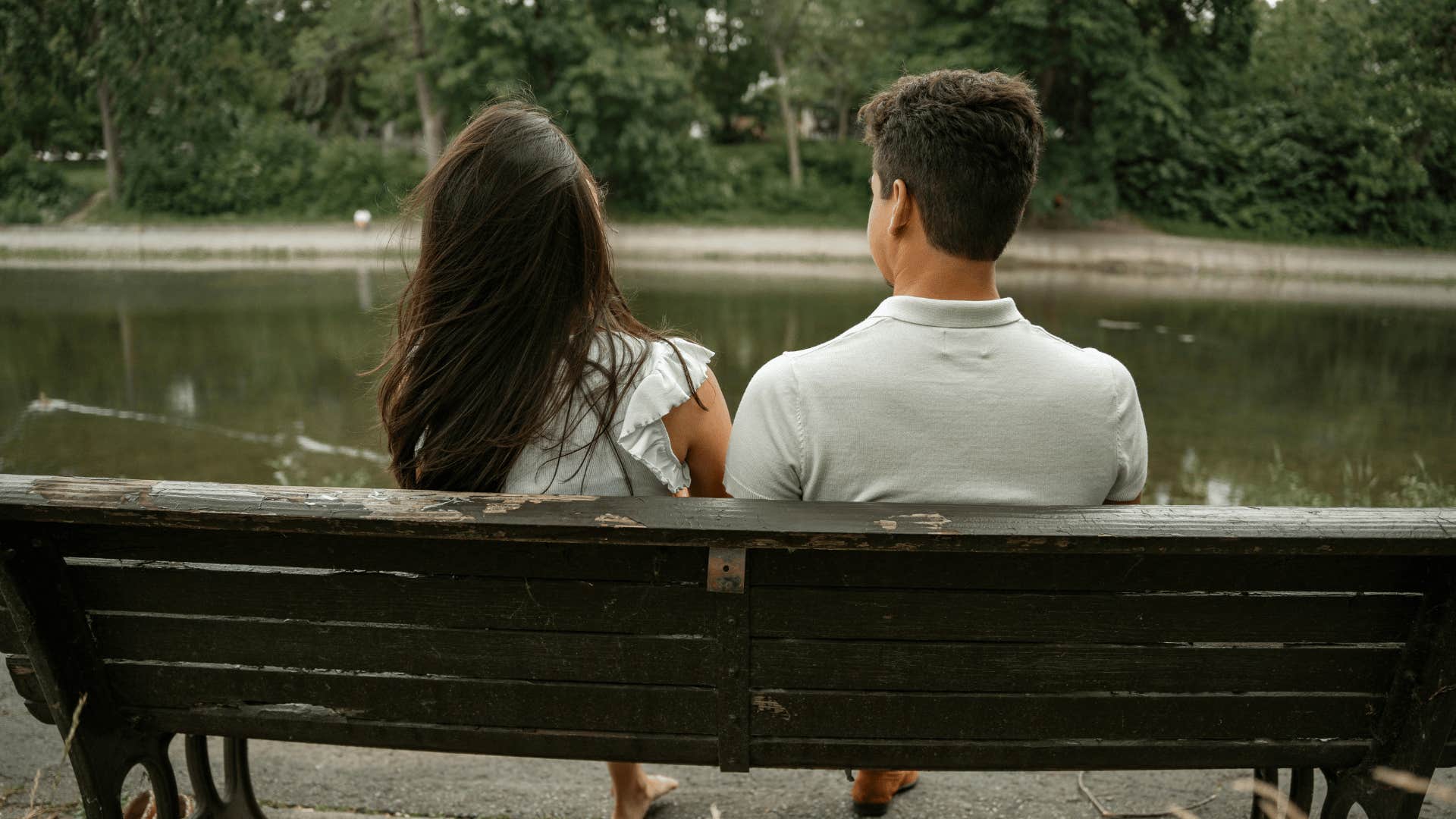 couple sitting on bench by lake