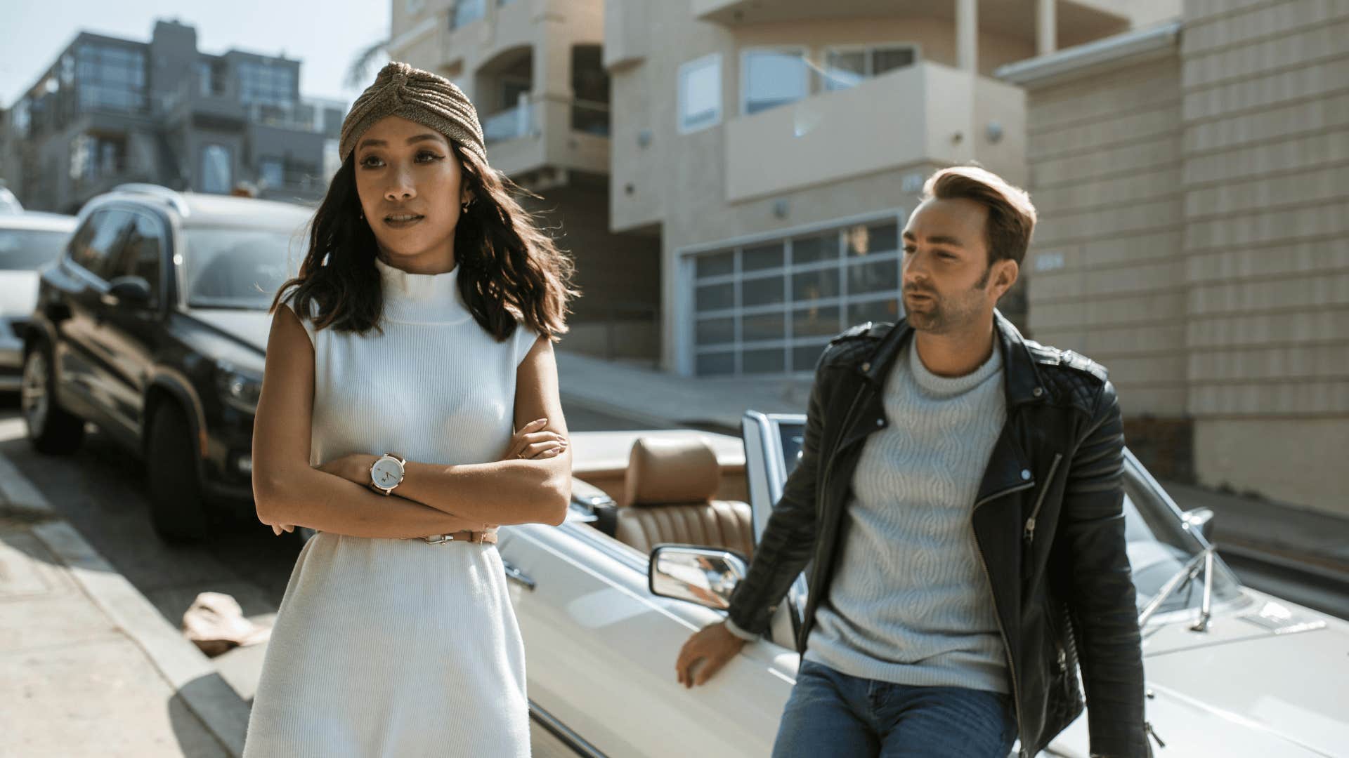 woman turned away from man leaning on car