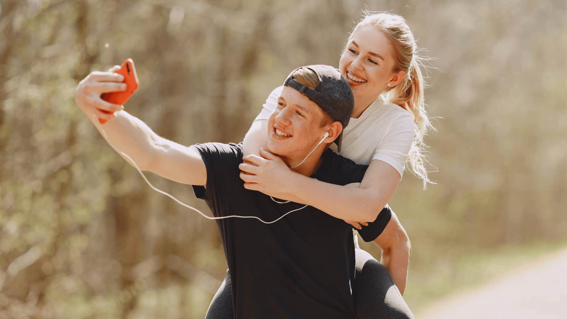 man giving woman piggyback ride and taking selfie